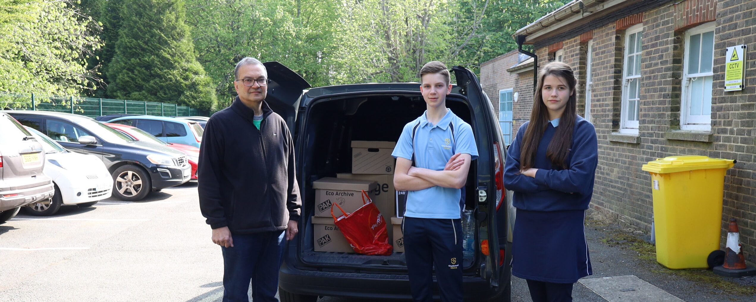 Boy and girl in front of a van full of boxes with man