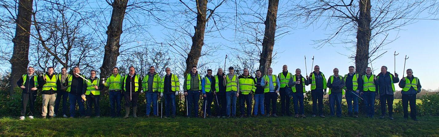 Group of people in high vis jacket picking up rubbish in field